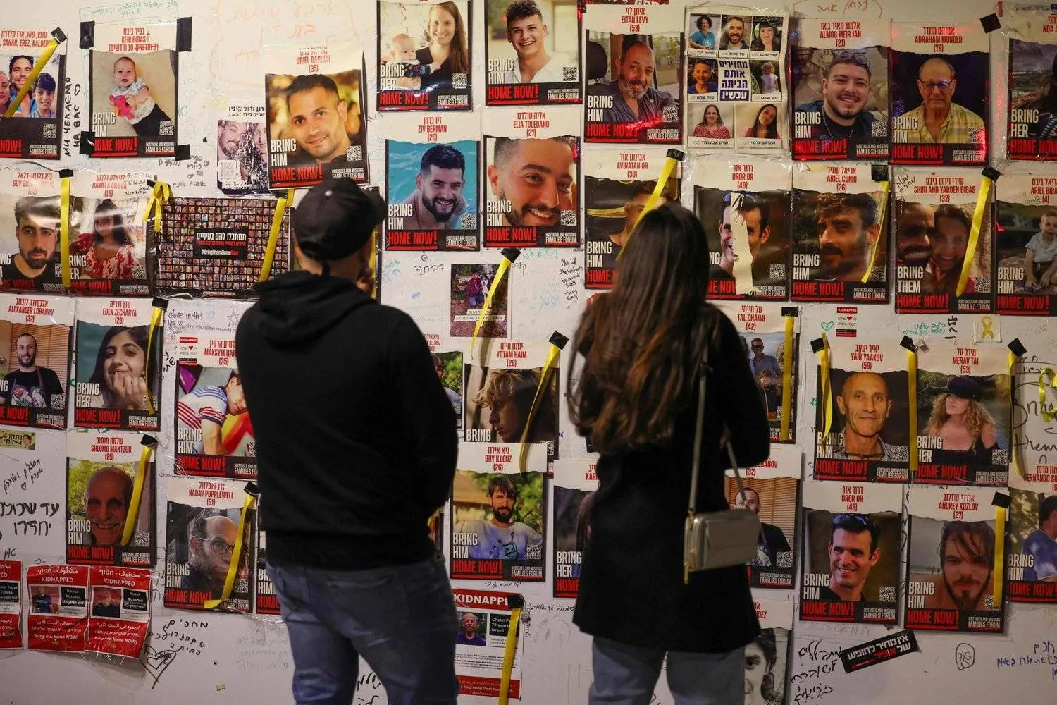 صور الرهائن الإسرائيليين المحتجزين في غزة منذ هجوم 7 أكتوبر معلقة على جدار في تل أبيب (أ.ف.ب)