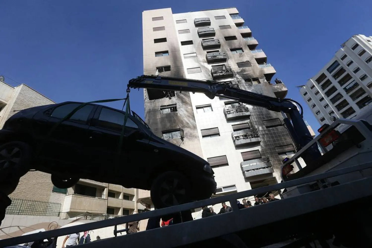 A car is removed from the area where reported Israeli air strikes targeted a residential building in the Kafr Sousa district of the Syrian capital Damascus on February 21, 2024. (AFP)
