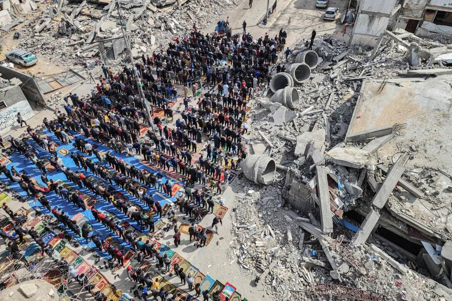 In this aerial view, Palestinians attend the Friday noon prayers in front of the ruins of the al-Faruq mosque, destroyed in Israeli strikes in Rafah in the southern Gaza Strip on March 1, 2024, amid continuing battles between Israel and the Palestinian militant group Hamas. (AFP)