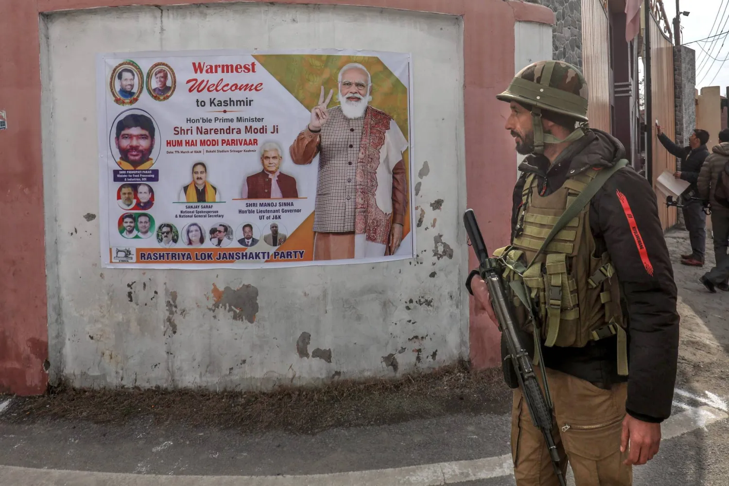 شرطي هندي يسير أمام ملصق لرئيس الوزراء ناريندرا مودي خارج ملعب باكشي في كشمير (إ.ب.أ)
