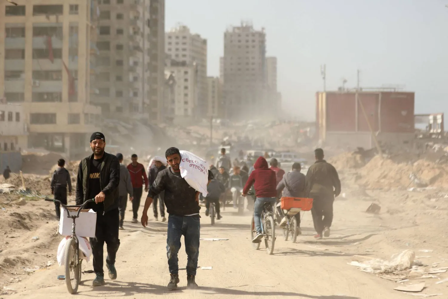 غزيون يحملون أكياس طحين كانت جزءاً من مساعدات دخلت مدينة غزة  (أ.ف.ب)