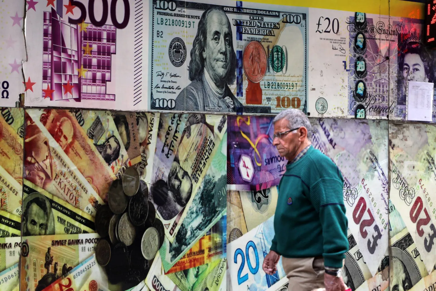 مصري يسير أمام محل صرافة بالقاهرة (إ.ب.أ)