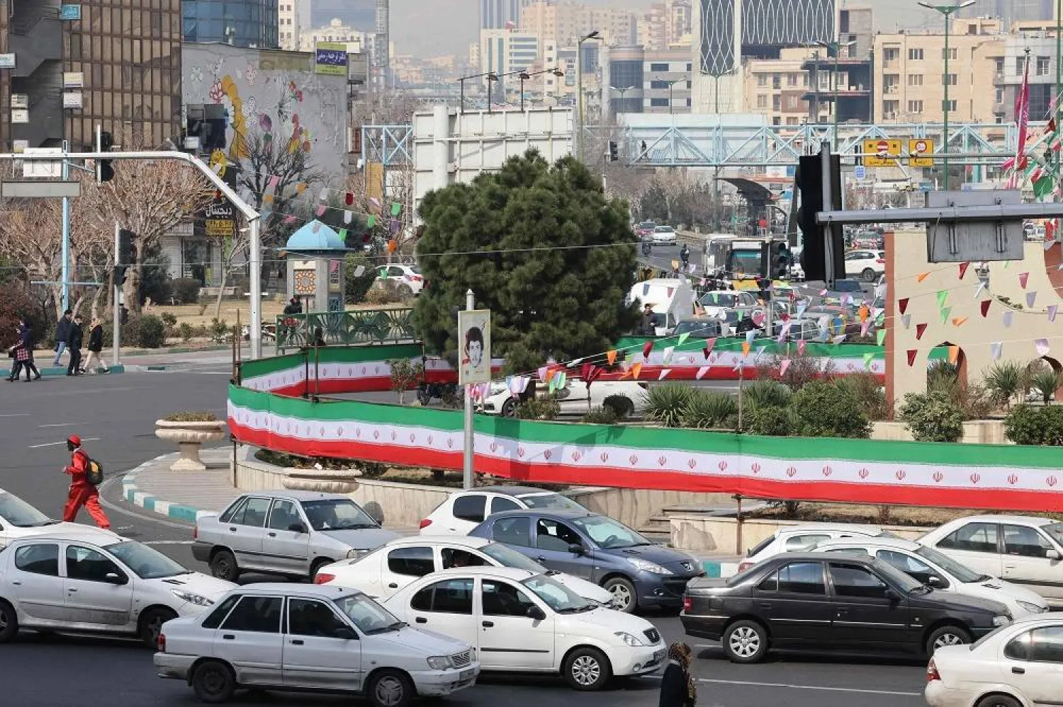 Cars drive past a wall covered by a banner in the colors of the national flag in Tehran on March 3, 2024, two days after Iranians voted in the country's parliamentary election. (AFP)