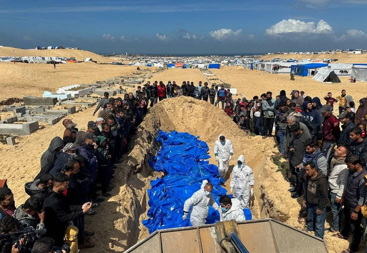 People bury the bodies of Palestinians killed in Israeli strikes and fire, after their bodies were released by Israel, amid the ongoing conflict between Israel and the Palestinian group Hamas, at a mass grave in Rafah, in the southern Gaza Strip, March 7, 2024. (Reuters)