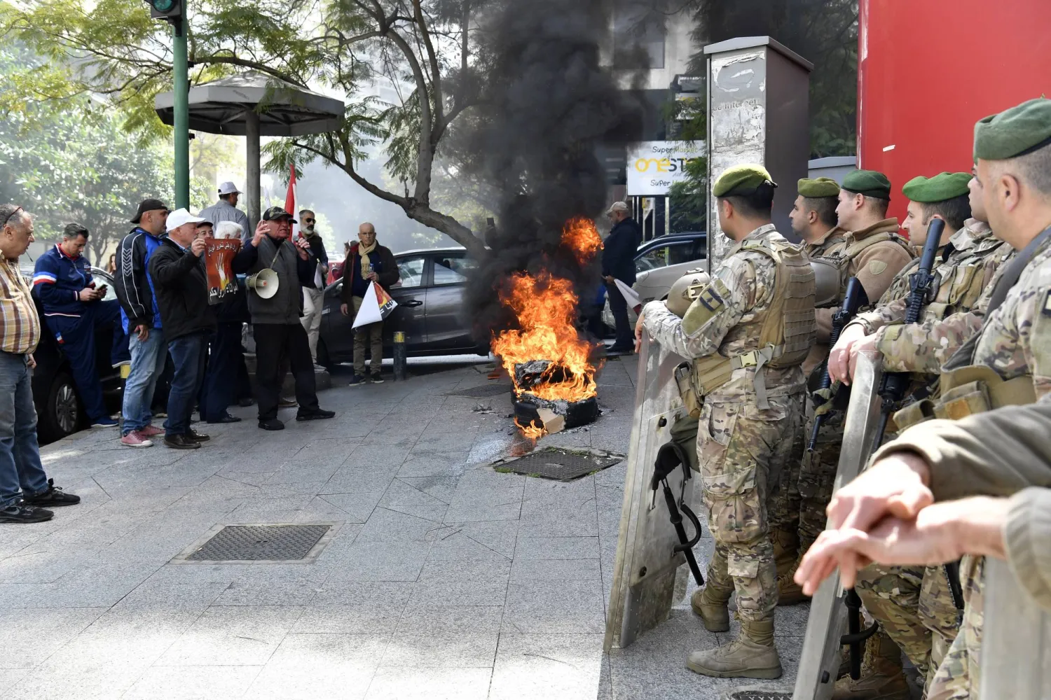 عسكريون يقومون بحماية أحد المصارف خلال قيام عدد من المودعين بإحراق الإطارات المشتعلة (إ.ب.أ)