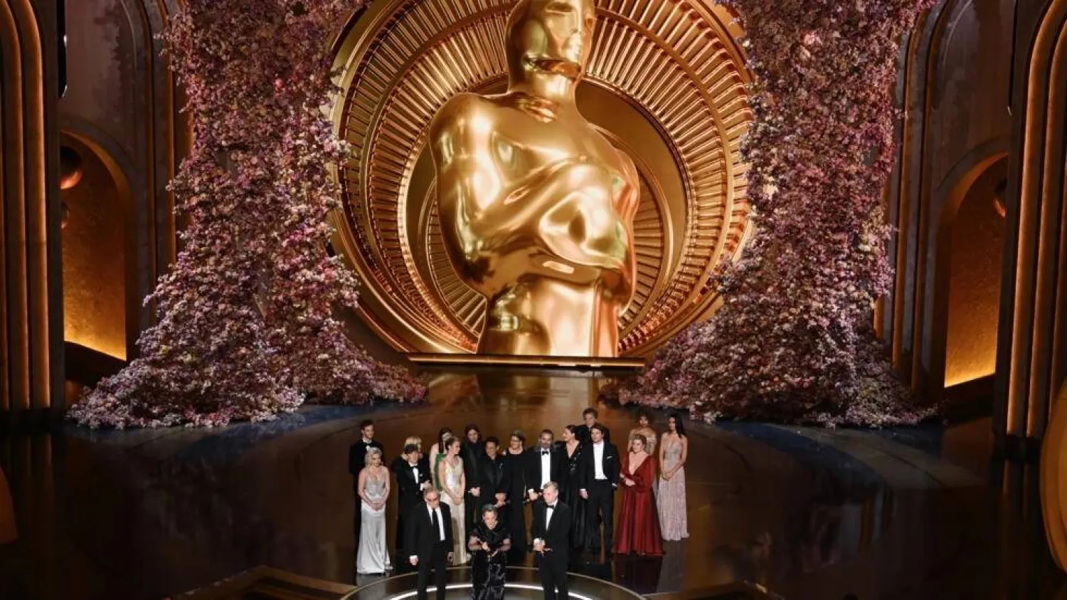 'Oppenheimer' producer Emma Thomas (C), producer Charles Roven (L) and director Christopher Nolan accept the best picture Oscar, with the cast behind them. Patrick T. Fallon / AFP
