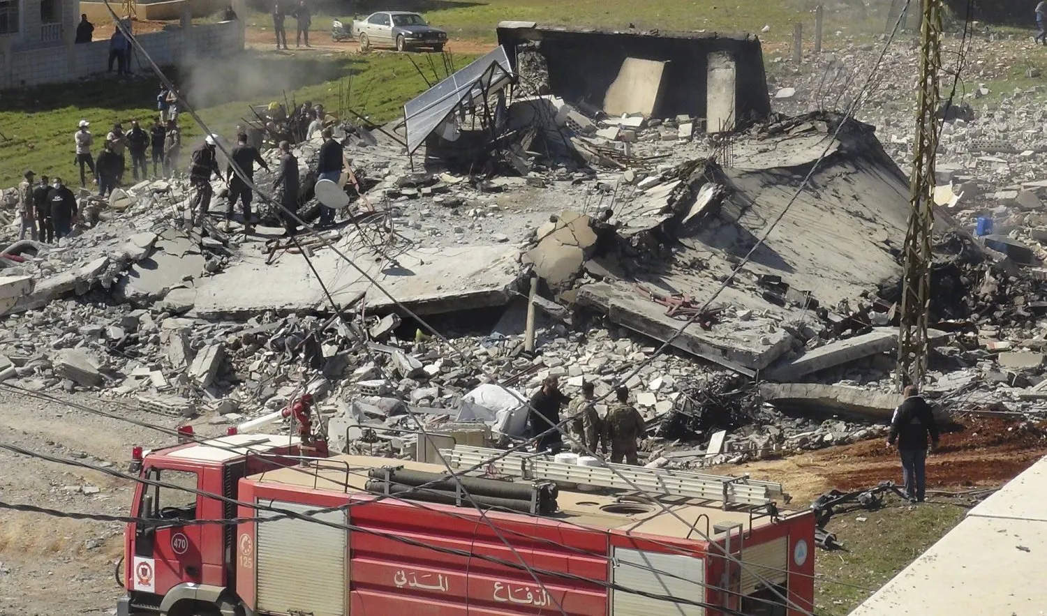 Sivil Savunma ve İtfaiye Teşkilatı üyeleri, Lübnan'ın doğusundaki Baalbek bölgesinde İsrail saldırısı sırasında yıkılan bir evin yakınında (AP)