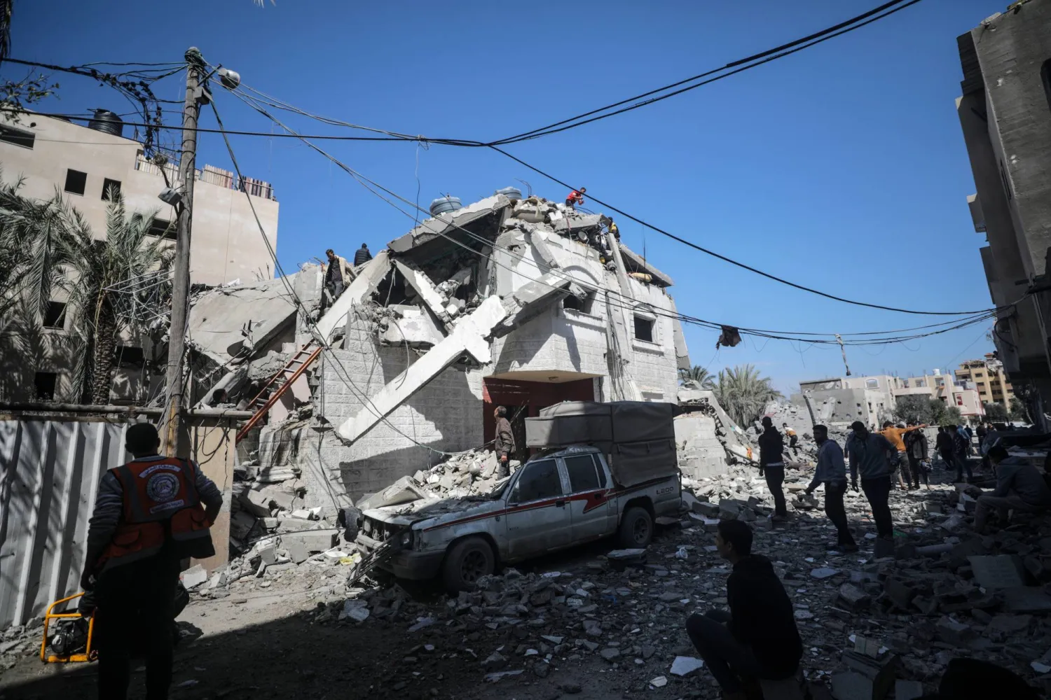 فلسطينيون ينقذون بعض ممتلكاتهم ويبحثون عن مفقودين تحت أنقاض منزل مدمر في أعقاب غارة جوية إسرائيلية على بلدة دير البلح (إ.ب.أ)