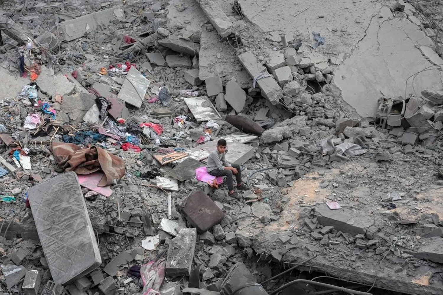 A boy sits among the rubble and scattered belongings of the Palestinian al-Atrash family, after their home was destroyed in an Israeli strike in Deir al-Balah in the central Gaza Strip on March 13, 2024, amid the ongoing conflict between Israel and the Hamas group. (AFP)