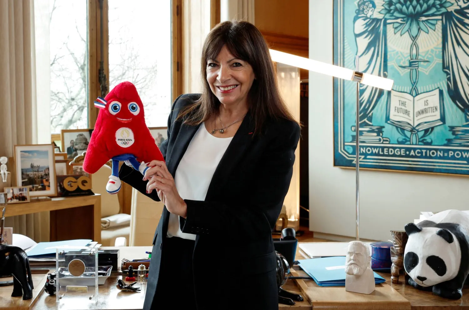 آن هيدالغو رئيسة بلدية باريس تحمل تميمة أولمبياد باريس 2024 (رويترز)