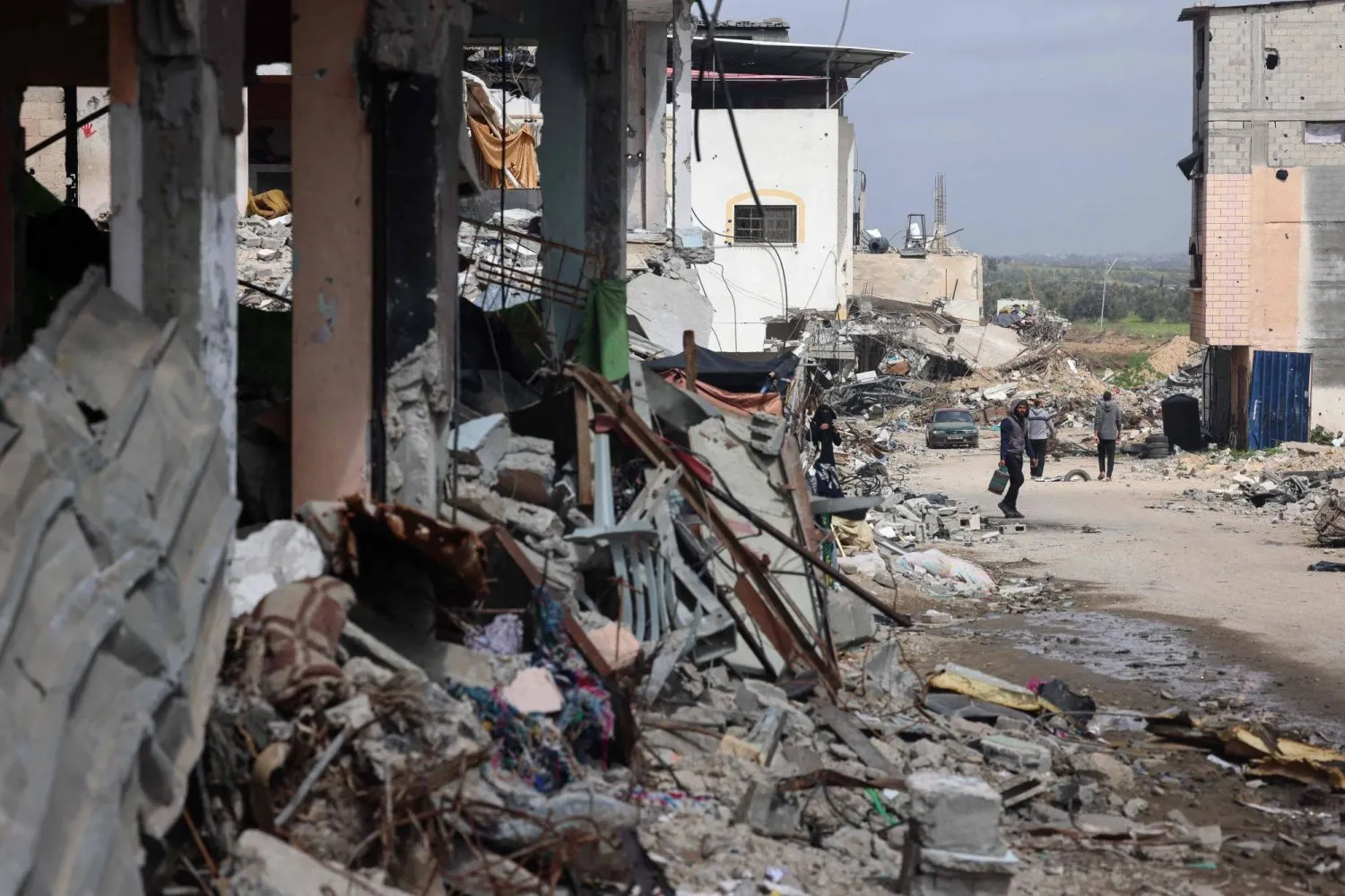 Filistinliler, İsrail'in Gazze Şeridi'nin merkezindeki Bureyc mülteci kampını hedef aldığı yerde yürüyor (AFP)