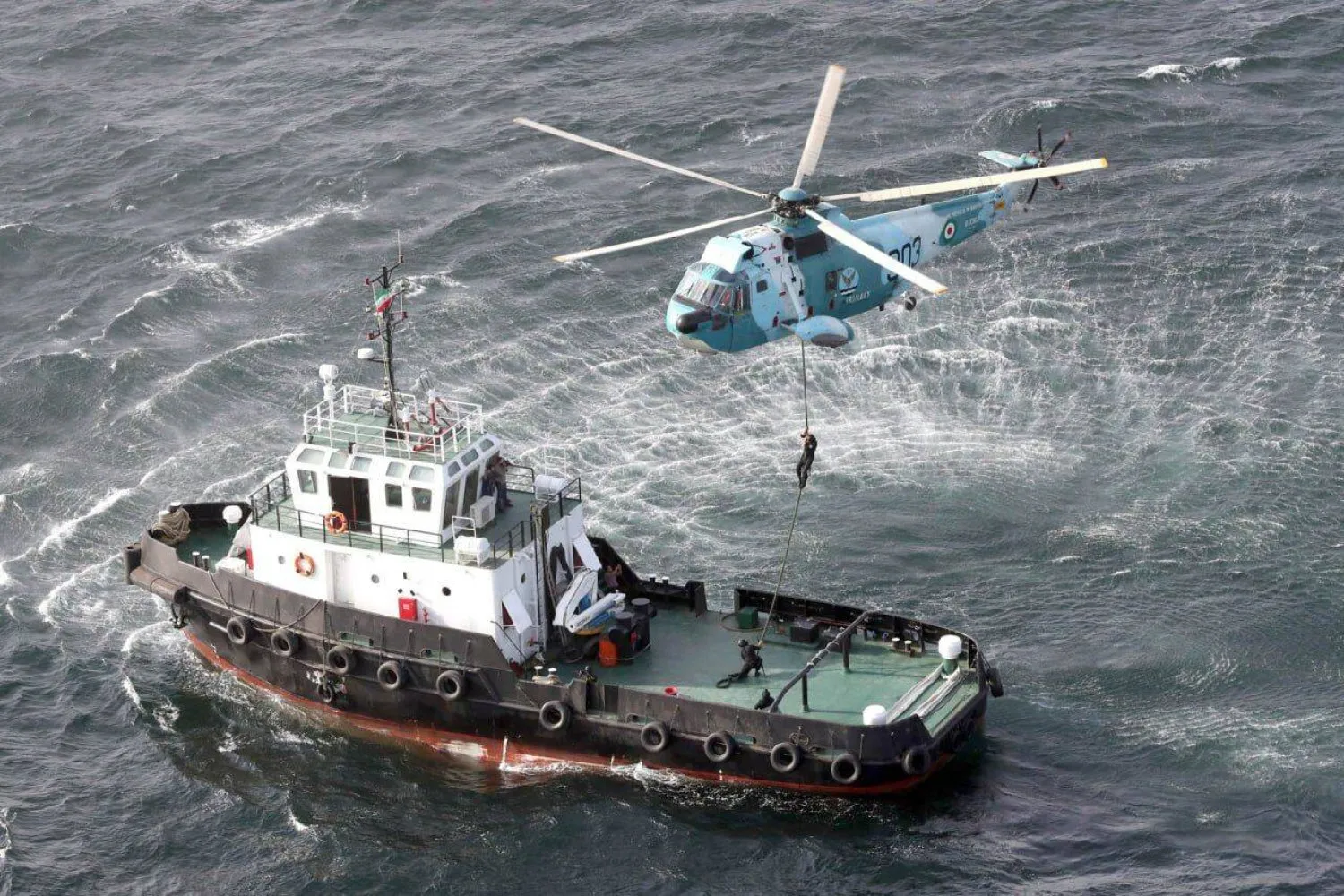 An SH3D helicopter of the Iranian Navy flies over a ship during joint exercises with Russia and China in the Gulf of Oman (IRNA)