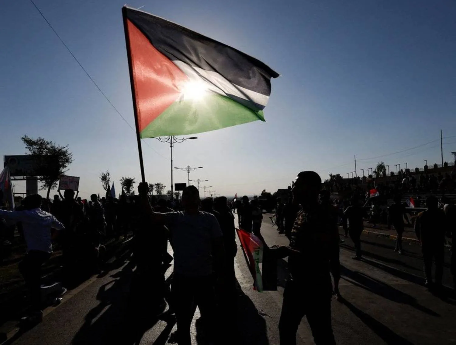 A man holds the Palestinian flag during a protest in solidarity with Palestinians in Gaza, in Mosul, Iraq, October 14, 2023. (Reuters)
