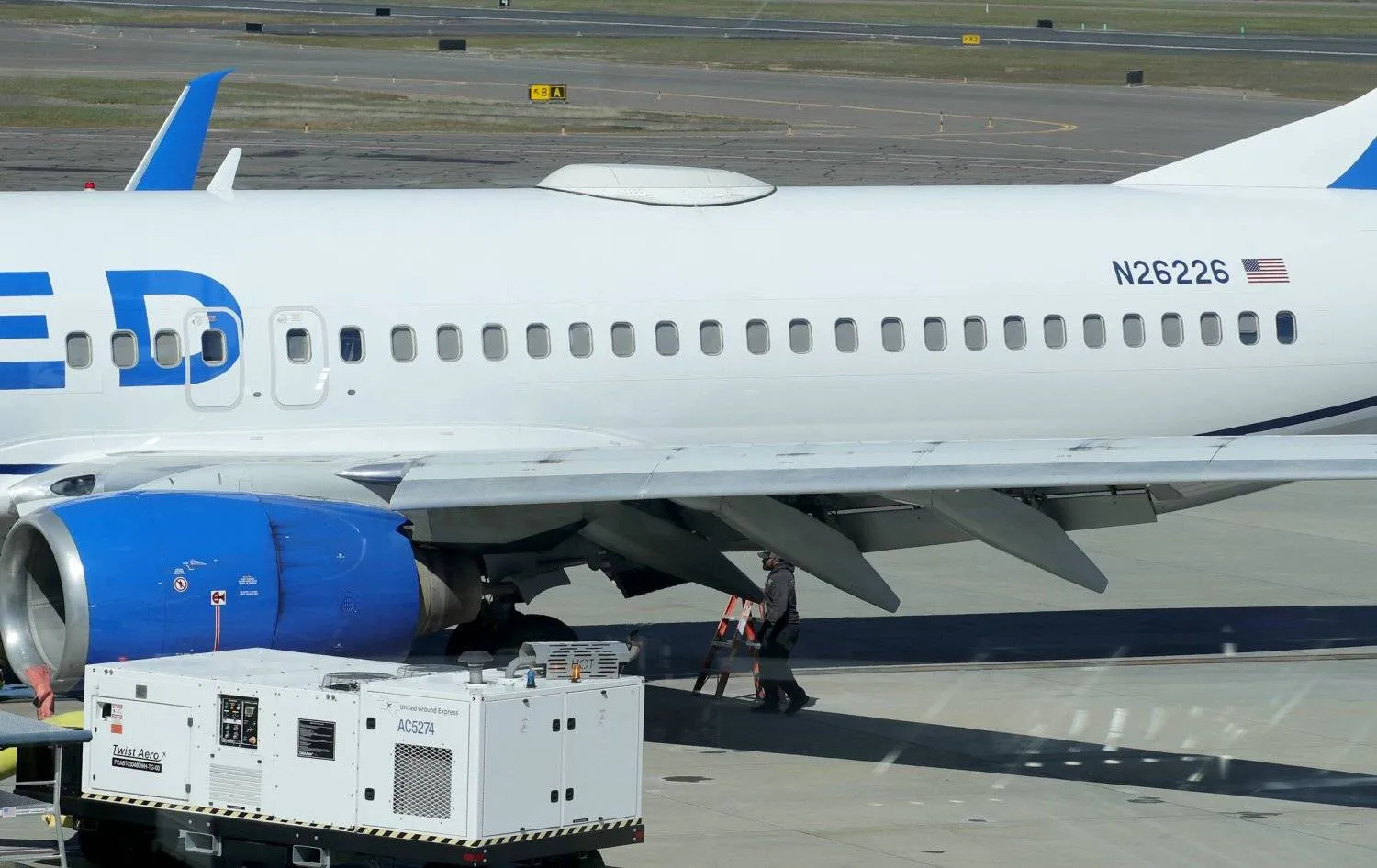 A worker walks under the Boeing plane that landed at Rogue Valley International Airport-Medford after a flight from San Francisco with a missing panel(AP)