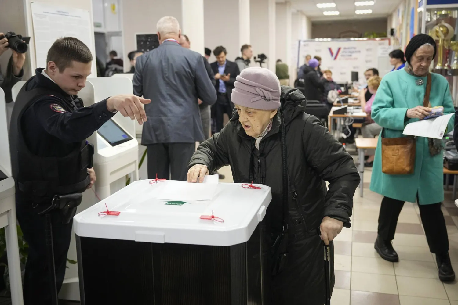 Police officer explains a woman how to cast a ballot during a presidential election in Moscow, Russia, Saturday, March 16, 2024. (AP Photo/Alexander Zemlianichenko)