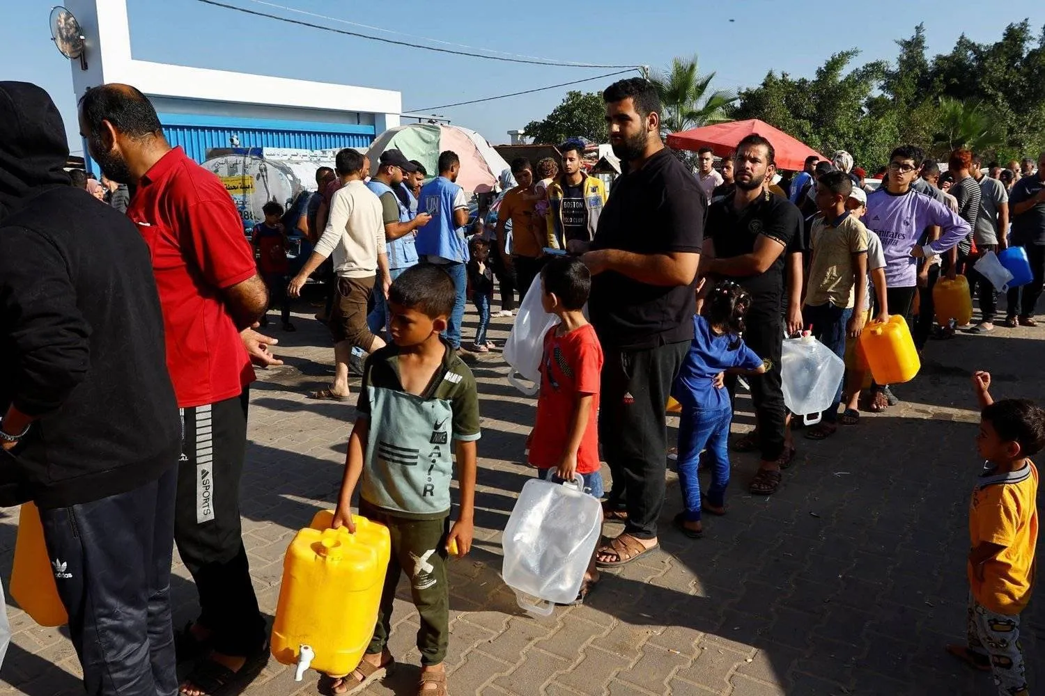 فلسطينيون يصطفّون للحصول على المياه بينما يحتمون في مخيم تديره «الأمم المتحدة» في خان يونس (رويترز)