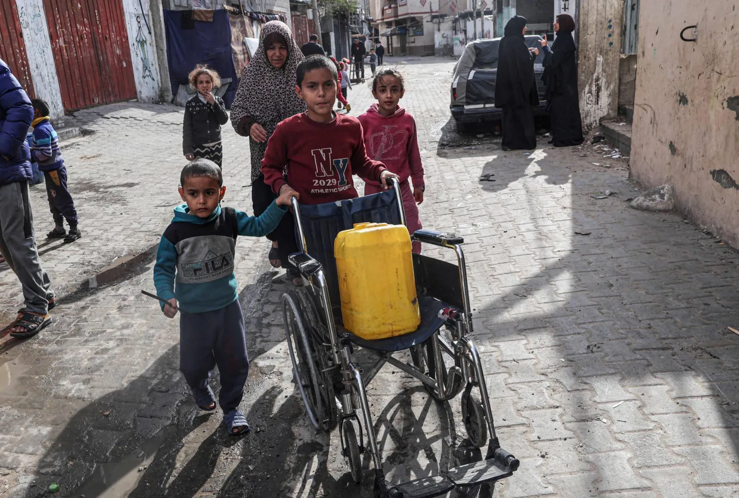 طفل فلسطيني ينقل عبوة من الماء على كرسي متحرك في رفح (أ.ف.ب)