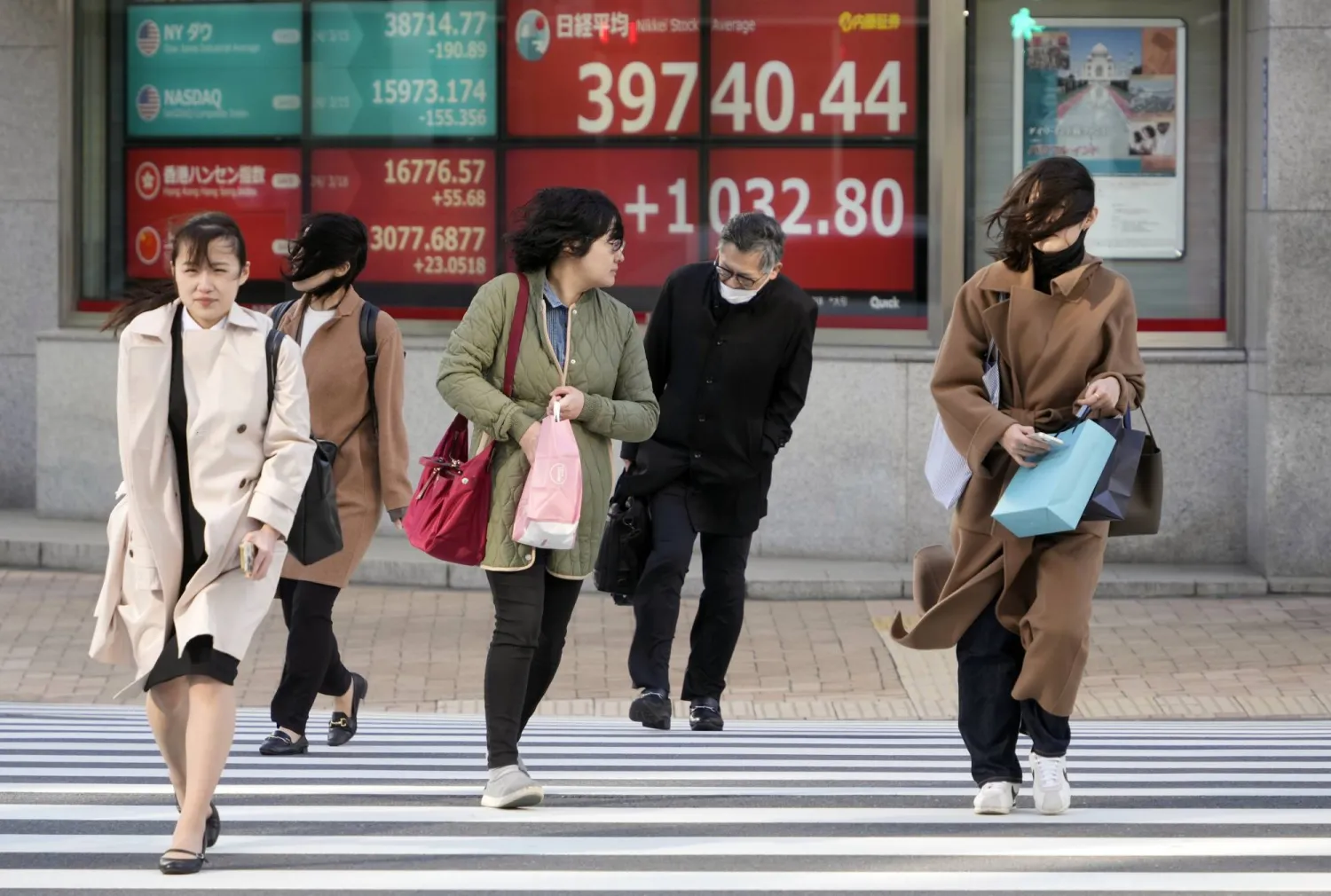 مشاة أمام شاشة تعرض تحركات الأسهم في أحد شوارع العاصمة اليابانية طوكيو (إ.ب.أ)