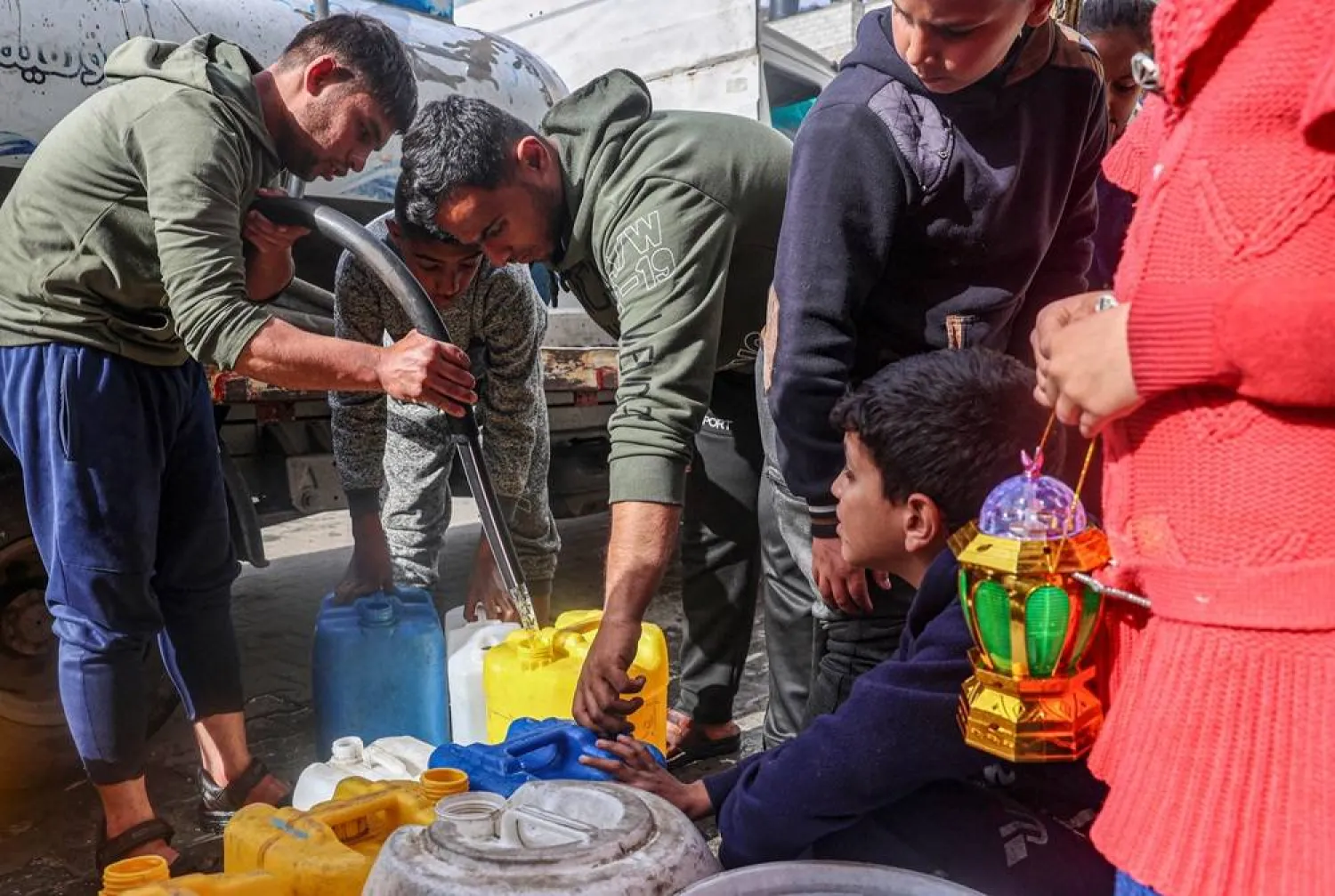  A girl holds a Ramadan lantern as Palestinians line up to fill containers with water in Rafah on the southern Gaza Strip on March 17, 2024, amid ongoing battles between Israel and Hamas. (AFP)