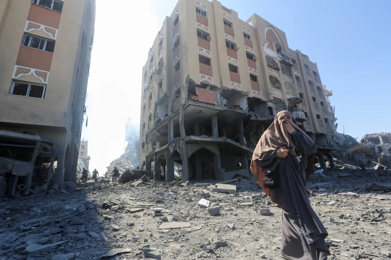 فلسطينية تسير أمام أحد المباني السكنية المتضررة عقب غارة إسرائيلية في خان يونس جنوب قطاع غزة (رويترز)