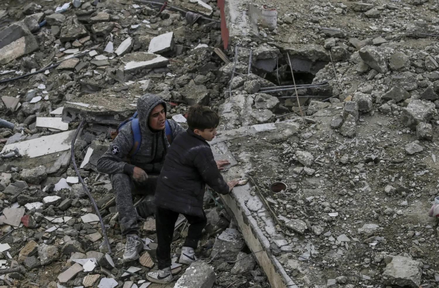 فلسطينيون يبحثون عن أحياء وسط الأنقاض المدمرة بفعل القصف الإسرائيلي في منزل عائلة الحاج بمخيم النصيرات جنوب قطاع غزة (إ.ب.أ)