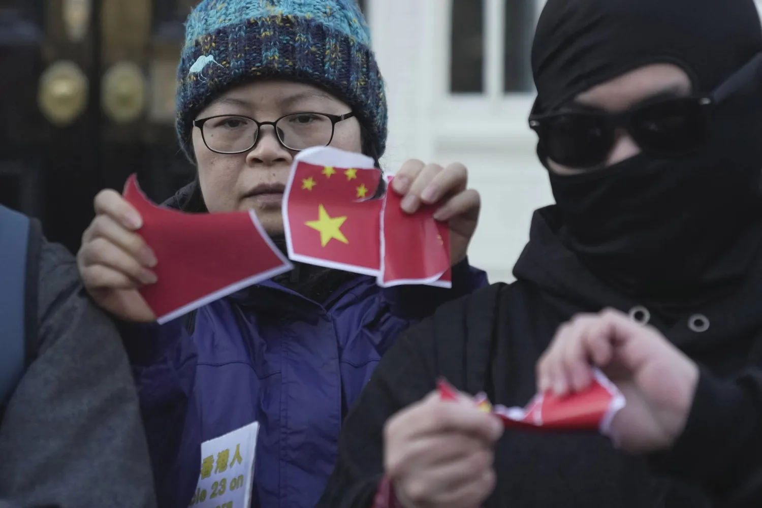 ناشطة من هونغ كونغ تمزق علم الصين خلال مظاهرة في لندن (أ.ب)