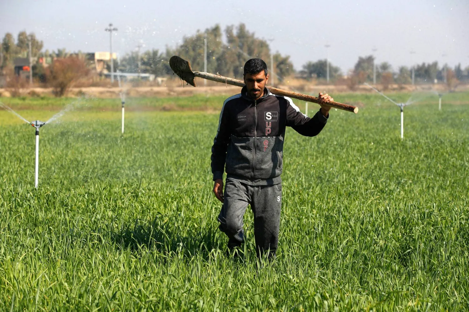 A farmer walks next to sprinklers, part of a new water management systems brought by the UN World Food Programme, on his farm in the village of al-Azrakiya, in Iraq's central province of Anbar, on February 22, 2024. (Photo by AHMAD AL-RUBAYE / AFP)