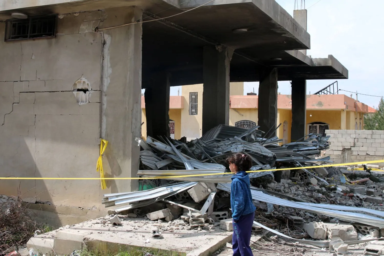 فتاة تعاين الأضرار التي لحقت بمنزل استهدف بغارة إسرائيلية قرب بعلبك فجر الأحد (أ.ف.ب)