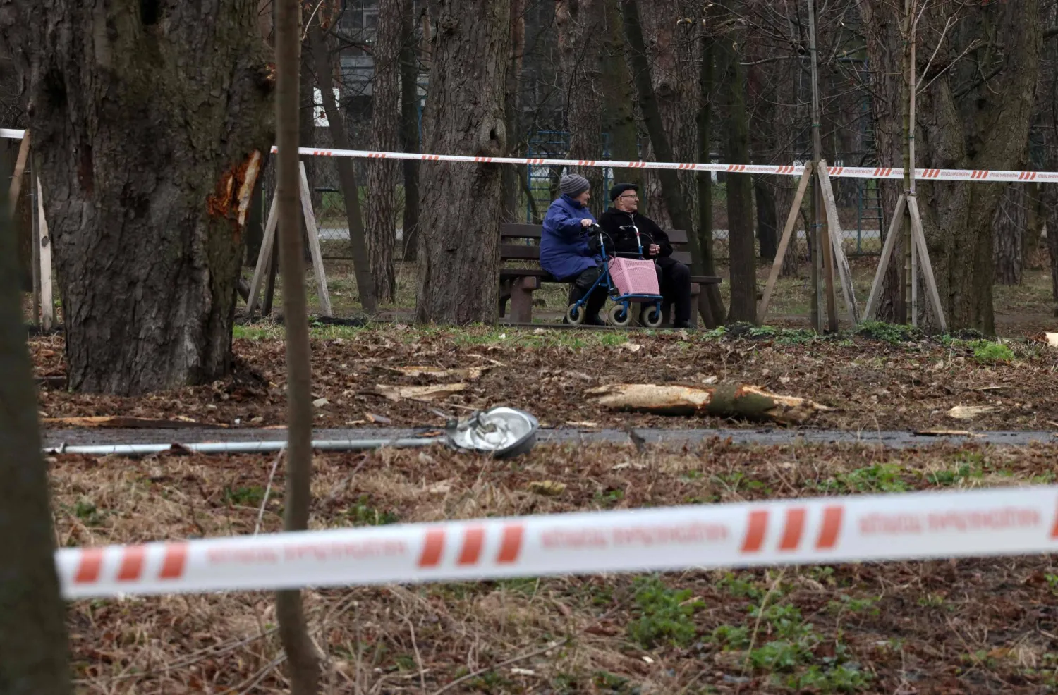 شخصان يجلسان في حديقة بكييف أصابها صاروخ روسي الأحد (أ.ف.ب)