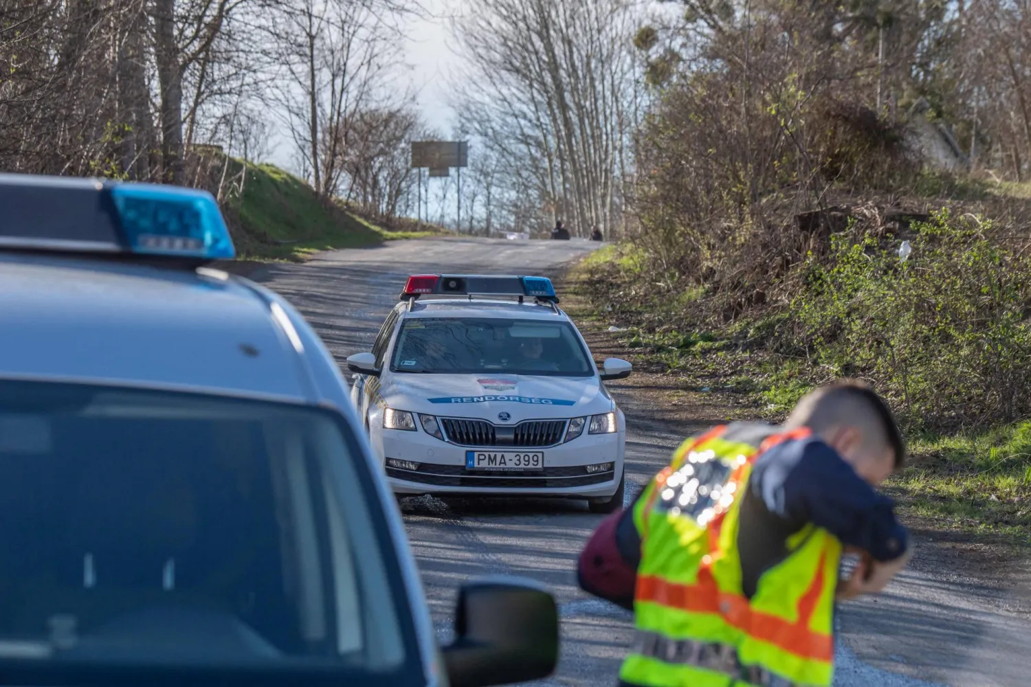 Hungarian police officers drive on a closed the road near the crash site where a vehicle taking part in the Esztergom Nyerges Rally veered off from the road on March 24, 2024, near Bajot, 55kms away from Budapest. (Photo by FERENC ISZA / AFP)