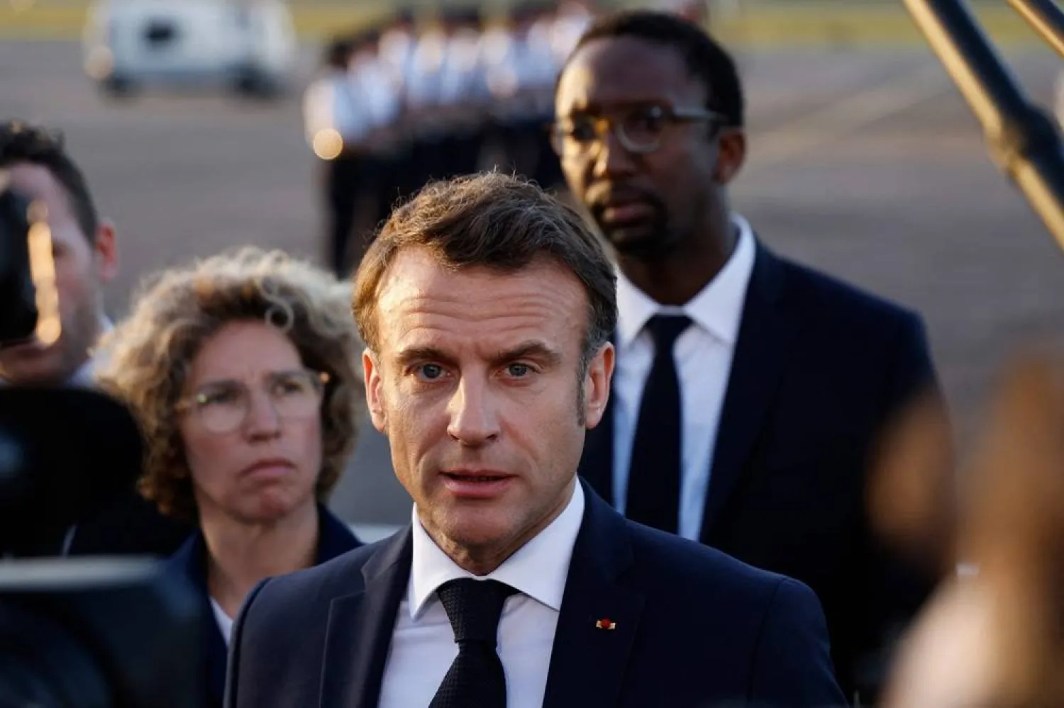 French President Emmanuel Macron, next to France's Deputy Minister for Overseas Territories Marie Guevenoux (L, background) and France's Secretary of State for the Sea and Biodiversity Herve Berville (R, background), speaks to the press upon his arrival at Cayenne-Felix Eboue airport in Cayenne, as part of a two-day visit to the French overseas department of Guiana, on March 25, 2024. (AFP) 