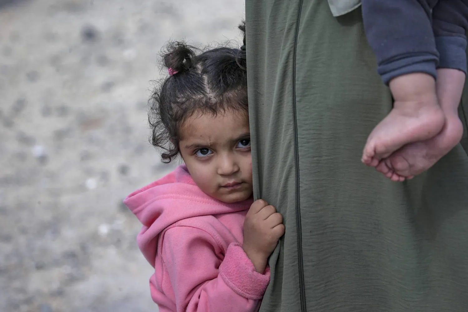 فتاة فلسطينية تقف بجوار والدتها على طريق الرشيد أثناء عبورهما من شمال قطاع غزة إلى جنوبه (إ.ب.أ)