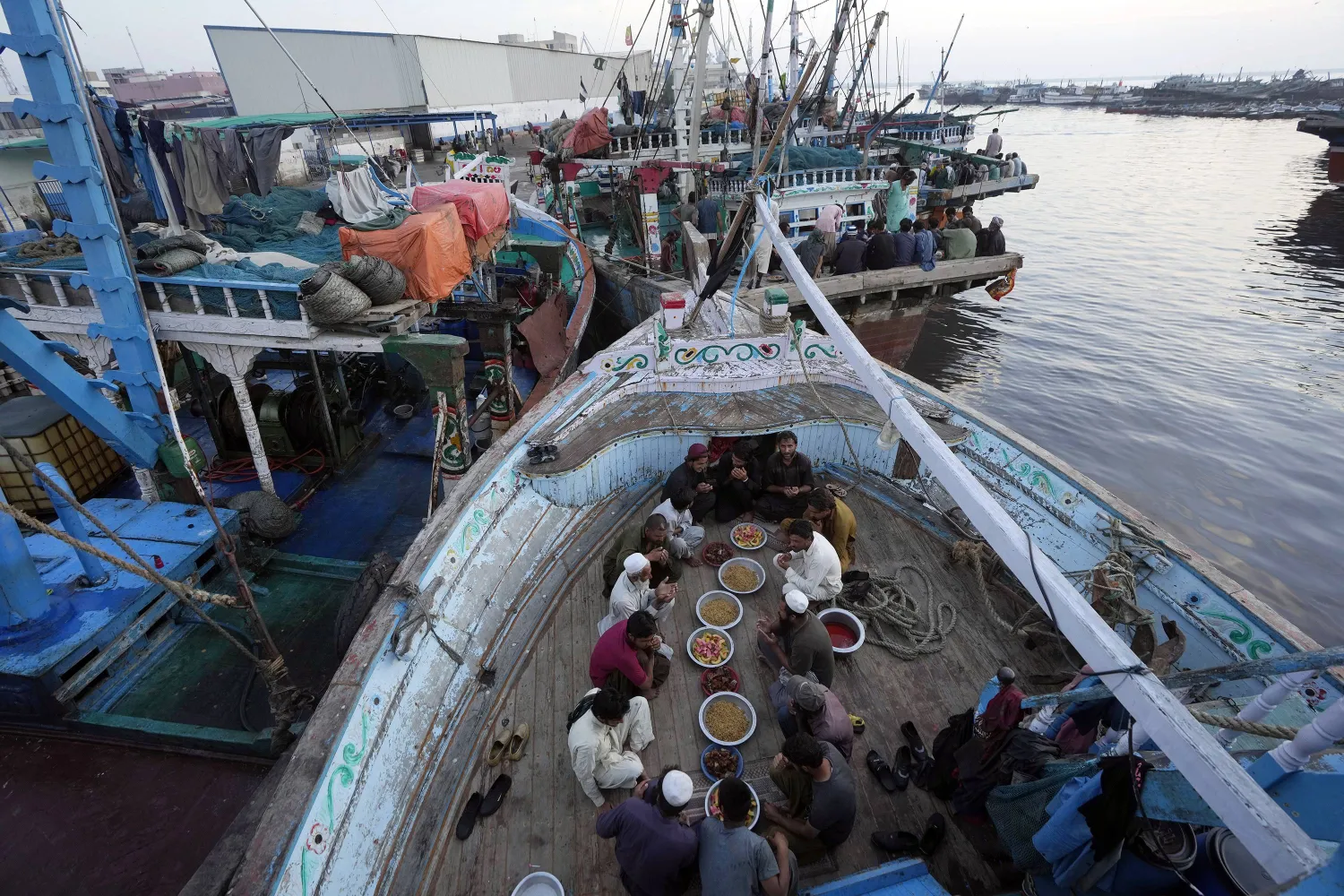 Pakistani fishermen pray before breaking their fast at a boat in the fish harbor on the Arabian Sea during the Muslim's holy fasting month of Ramadan, in Karachi, Pakistan, Sunday, March 24, 2024. (AP Photo/Fareed Khan)