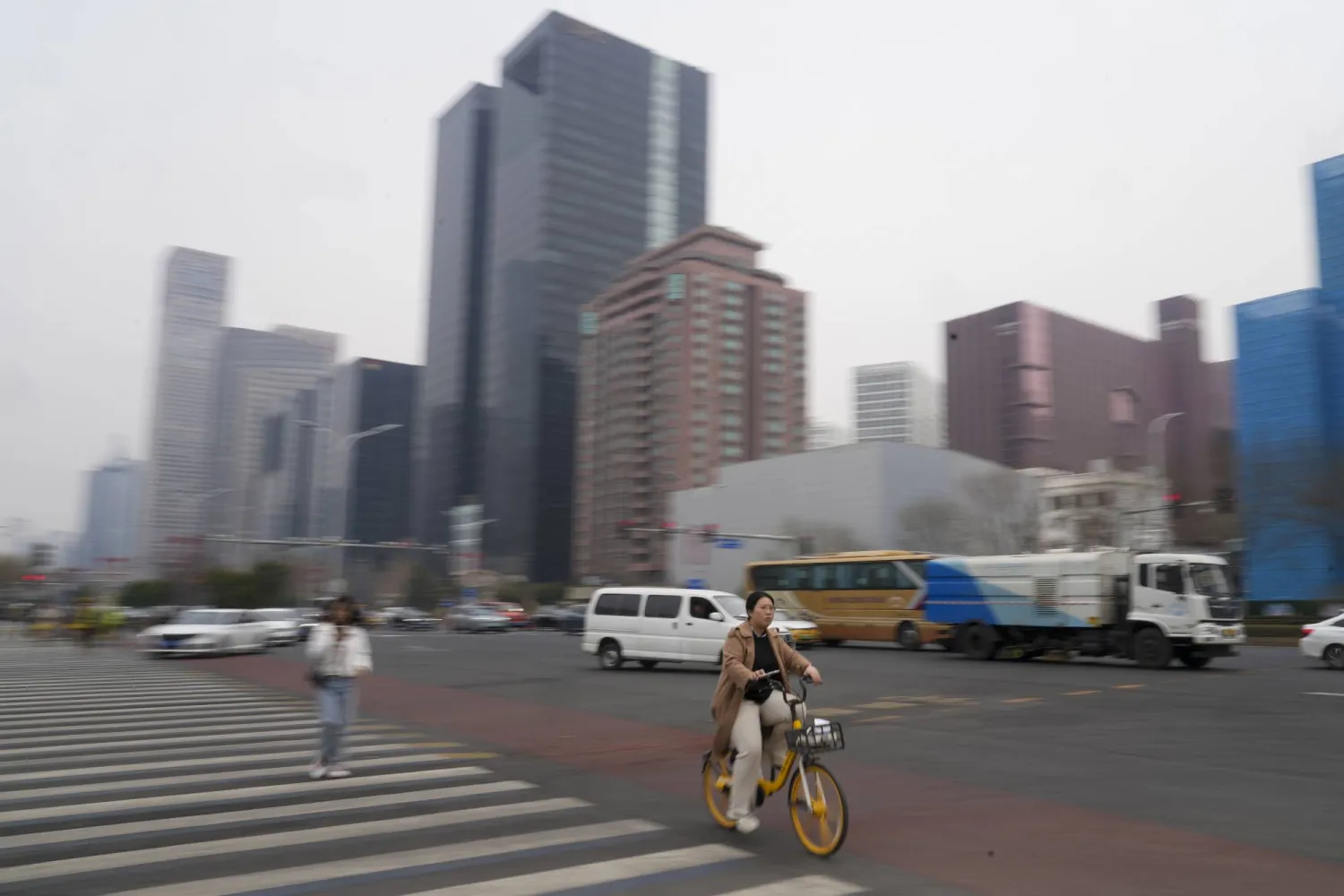 A cyclist rides near the main business district in Beijing, China, Saturday, March 23, 2024. (AP Photo/Tatan Syuflana)