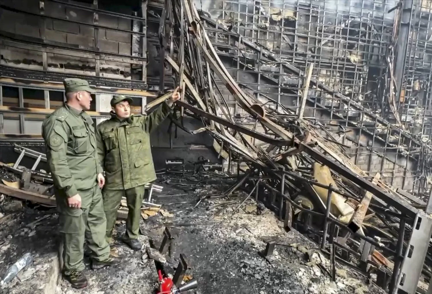 محققان روسيان داخل قاعة الحفلات الموسيقية المحترقة في ضاحية موسكو السبت (إ.ب.أ)