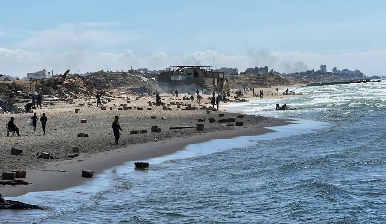  Palestinians gather on a beach as they collect aid airdropped by an airplane, amid the ongoing conflict between Israel and Hamas, in the northern Gaza Strip, March 25, 2024. (Reuters)