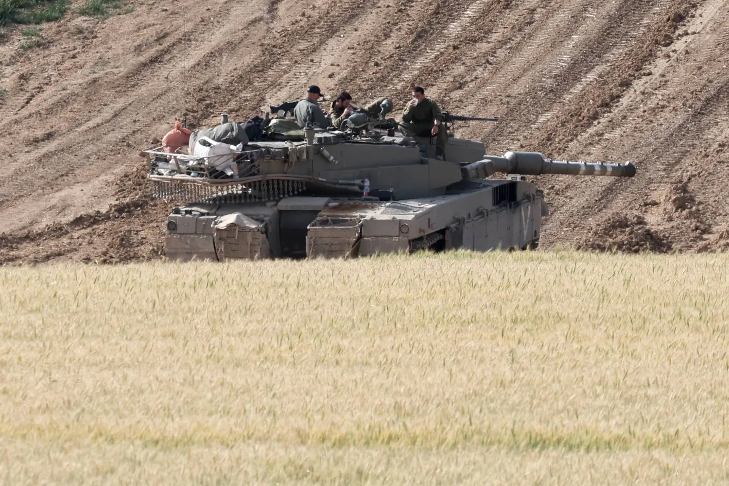 جنود إسرائيليون على متن دبابة عسكرية بالقرب من السياج الحدودي مع قطاع غزة كما يظهر من الجانب الإسرائيلي في جنوب إسرائيل في 26 مارس 2024 (إ.ب.أ)