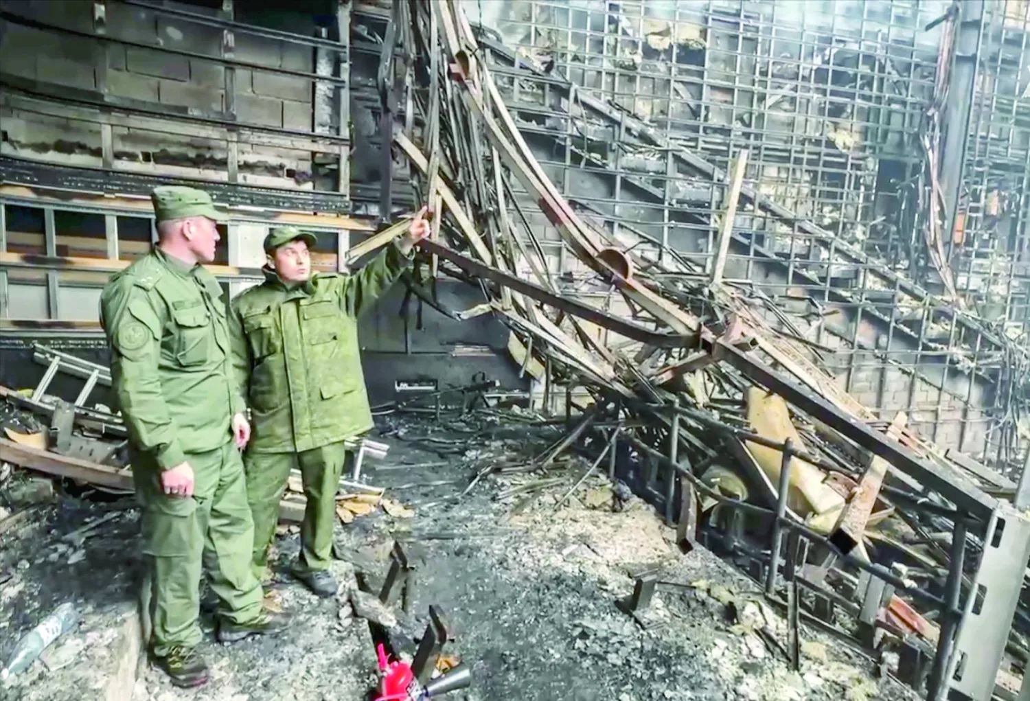 محققان روسيان داخل قاعة الحفلات الموسيقية المحترقة في ضاحية موسكو السبت (إ.ب.أ)