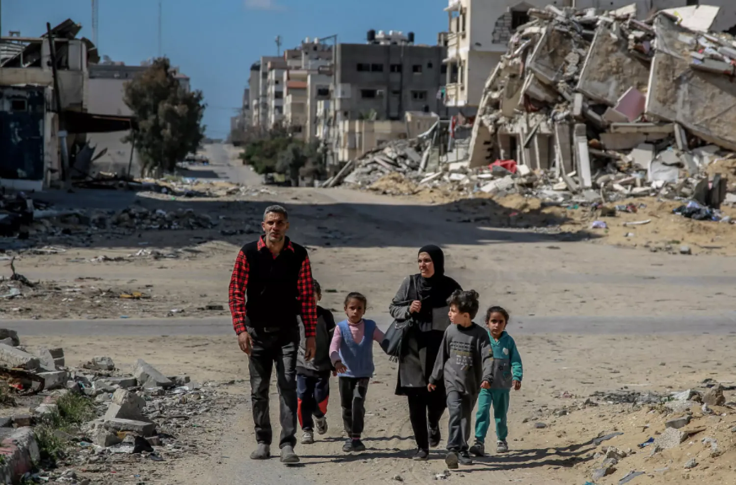 A Palestinian family walk past buildings destroyed in Gaza City, where the UN has warned that famine is imminent without a major intervention © - / AFP
