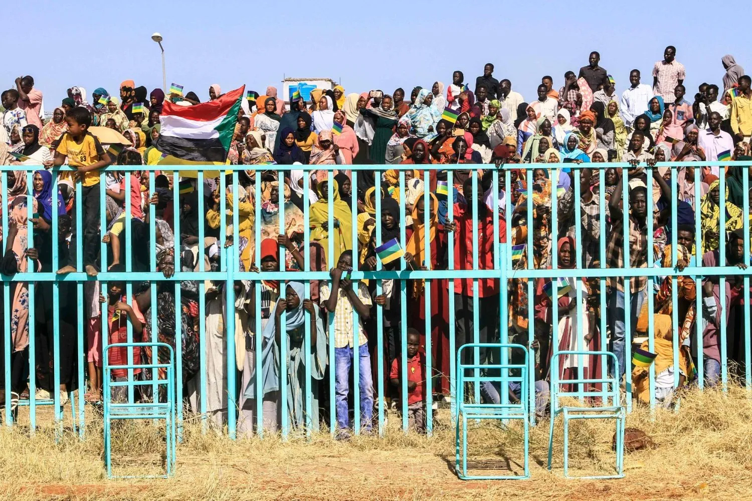 Dün (perşembe) el-Gadarif eyaletinde düzenlenen mezuniyet töreninde Sudan Ordusu Komutanı Korgeneral Abdulfettah el-Burhan'ı destekleyen silahlı bir grubun üyelerini izleyen Sudanlılar. (AFP)