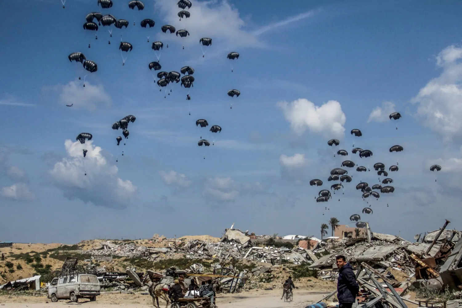 FILED - 25 March 2024, Palestinian Territories, Jabalia: Parachutes carrying humanitarian aid dropped from aircraft, land on Jabalia in northern Gaza Strip, where civilians are said to be on the verge of famine. Photo: Mahmoud Issa/dpa