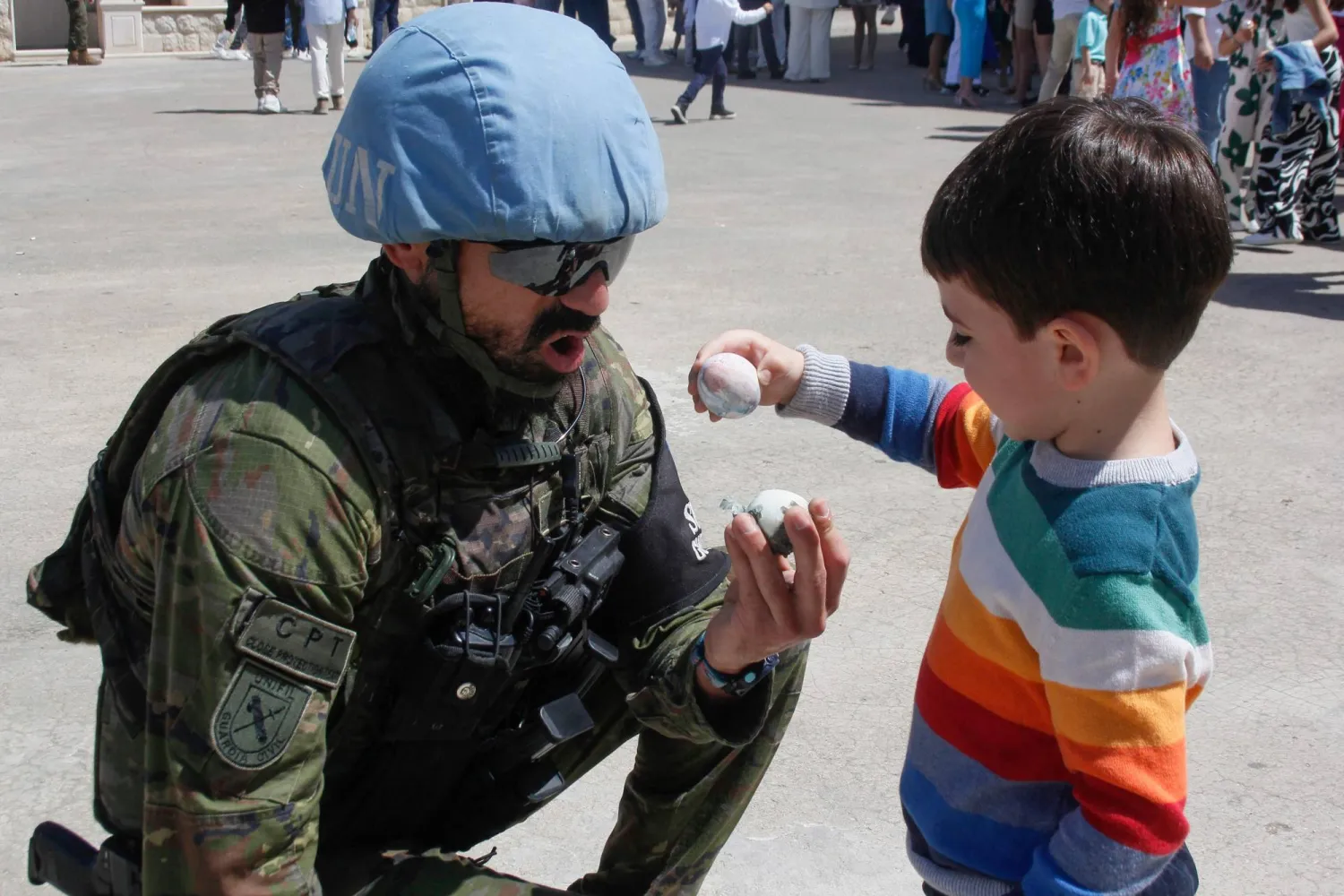 جندي إسباني من قوات «اليونيفيل» يحتفل مع طفل لبناني بـ«الفصح» في القليعة بجنوب لبنان (أ.ف.ب)