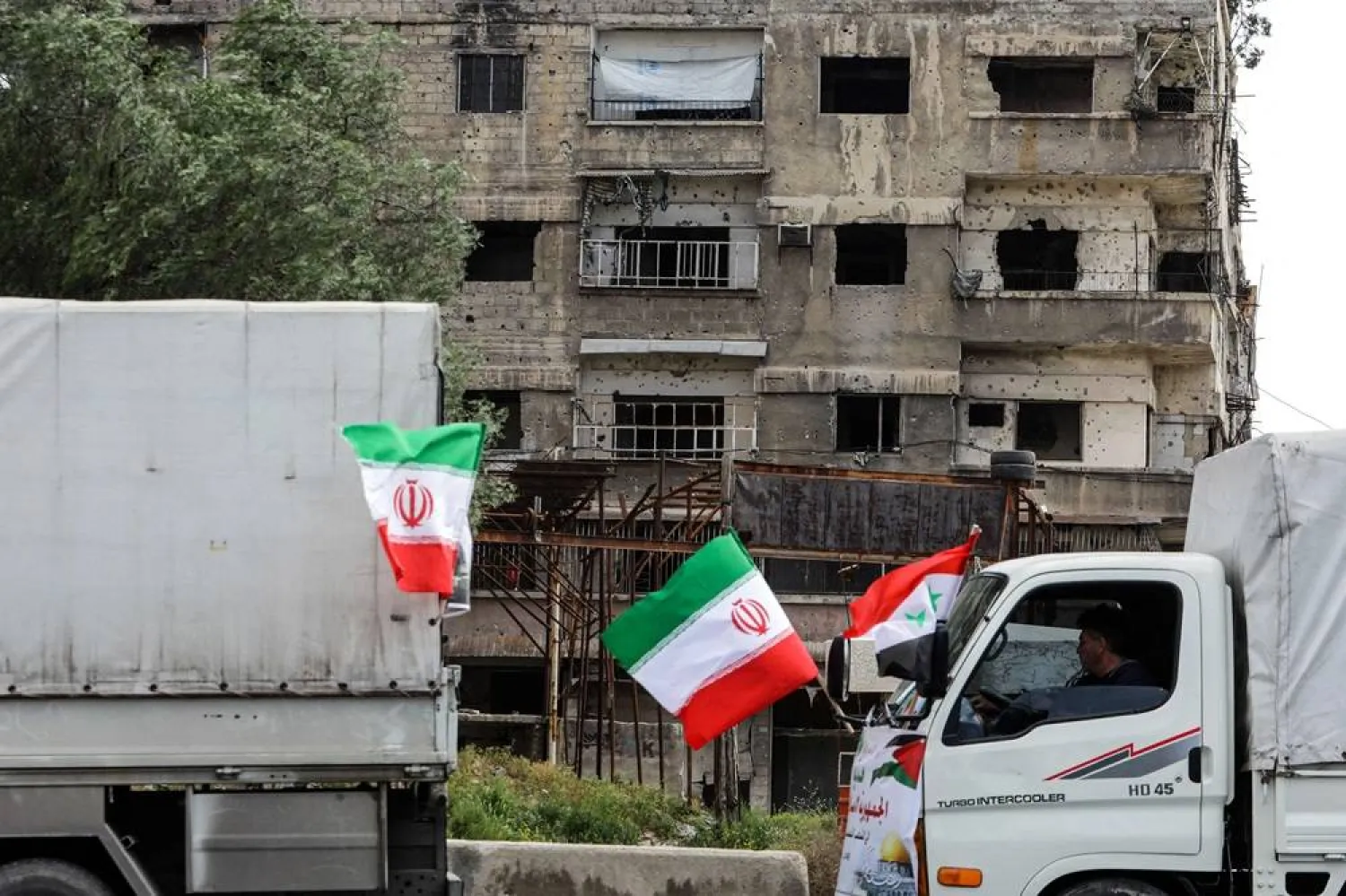  Trucks wait at the entrance of the Yarmuk camp for Palestinian refugees, south of Damascus, during a delivery of humanitarian aid provided by Iran as part of the Muslim holy fasting month of Ramadan on March 26, 2024. (AFP)