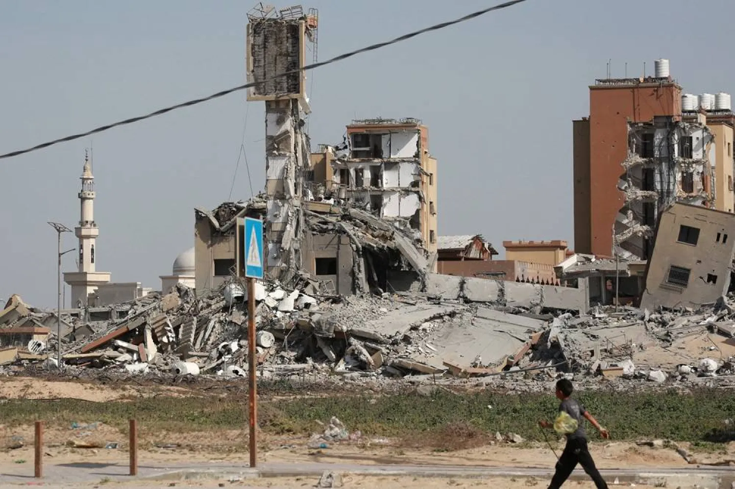  A youth walks past a building which was destroyed in previous Israeli bombardments in Nuseirat in the central Gaza Strip, on April 1, 2024, amid the ongoing battles Israel and Hamas. (AFP)