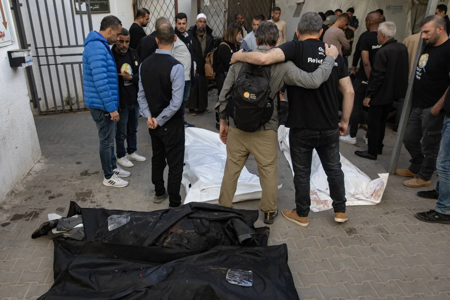 عمال المطبخ المركزي العالمي يتجمعون حول جثث زملائهم بعد نقلهم إلى مستشفى النجار في رفح (إ.ب.أ)