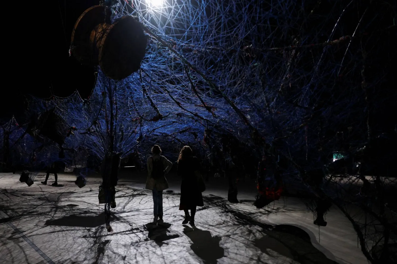People pass through an installation during the opening of the exhibition "Ground Break" by artist Nari Ward, at Pirelli HangarBicocca, in Milan, Italy, March 26, 2024. REUTERS/Claudia Greco