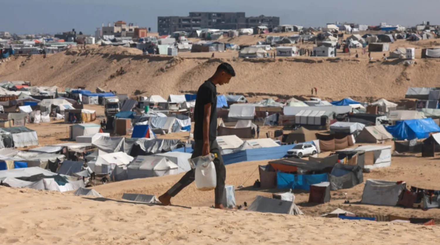 A Palestinian man ferries water at a makeshift camp for displaced people in Rafah in the southern Gaza Strip on April 4, 2024. © Mohammed Abed, AFP
