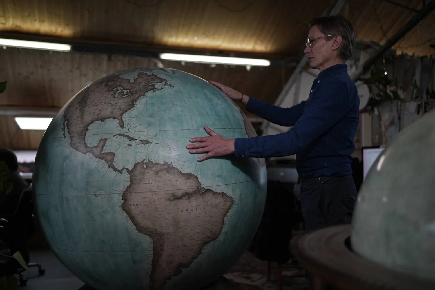 Peter Bellerby, the founder of Bellerby & Co. Globemakers, holds a globe at a studio in London, Tuesday, Feb. 27, 2024. (AP Photo/Kin Cheung)