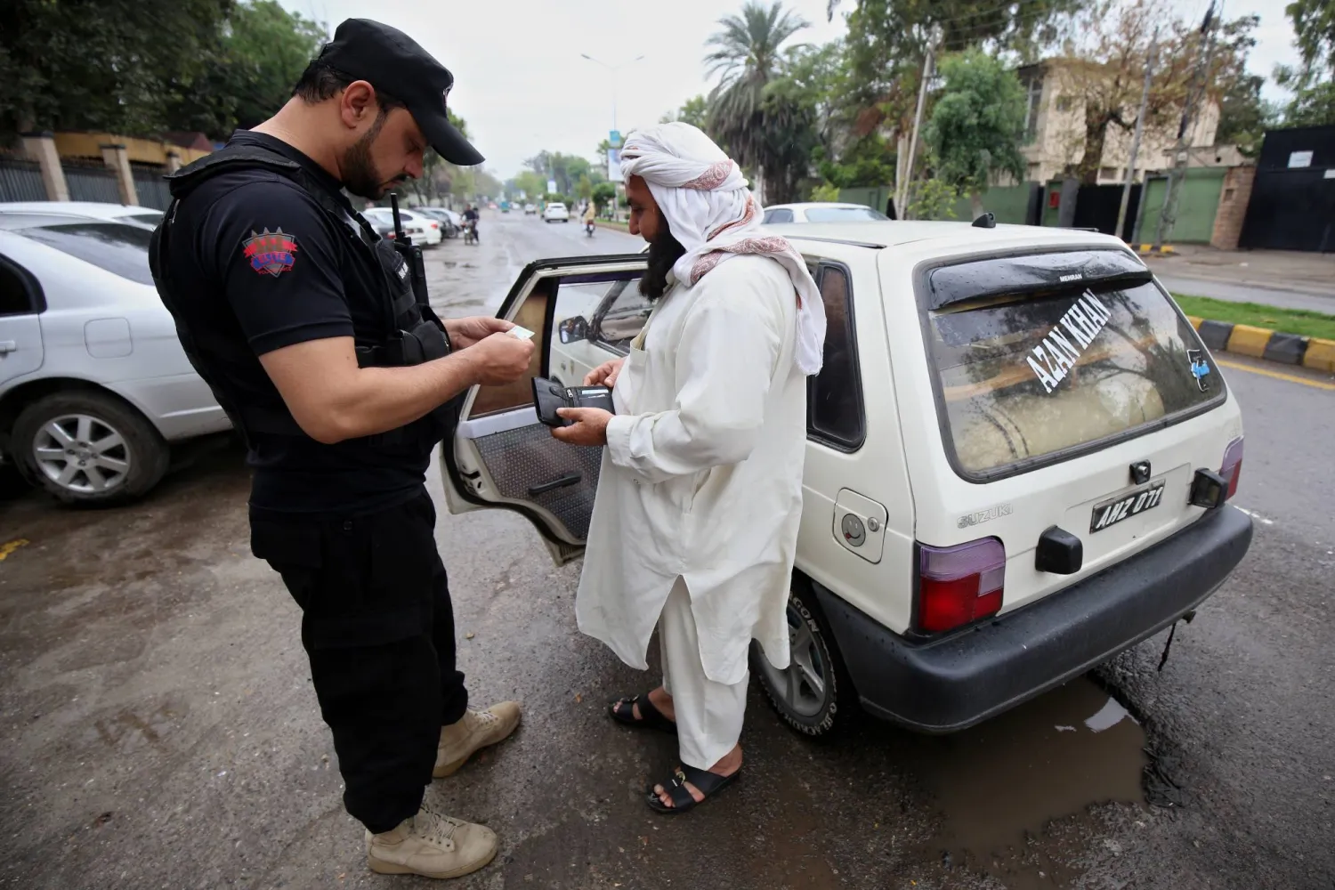مسؤول أمني باكستاني يفحص الأشخاص والمركبات عند نقطة تفتيش في أعقاب هجوم على مواطنين صينيين في بيشام - بيشاور عاصمة مقاطعة خيبر بختونخوا - باكستان 27 مارس 2024 (إ.ب.أ)