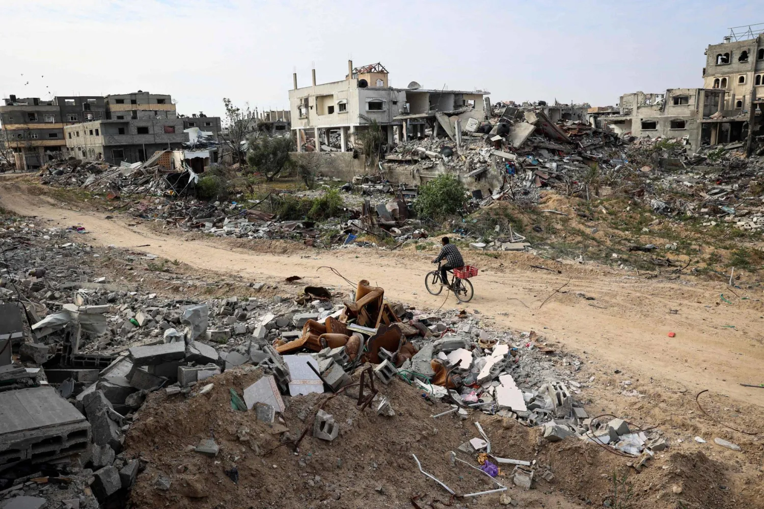 فلسطيني يركب درّاجة ويسير بين المباني المتضررة في خان يونس بقطاع غزة 8 أبريل 2024 (أ.ف.ب)